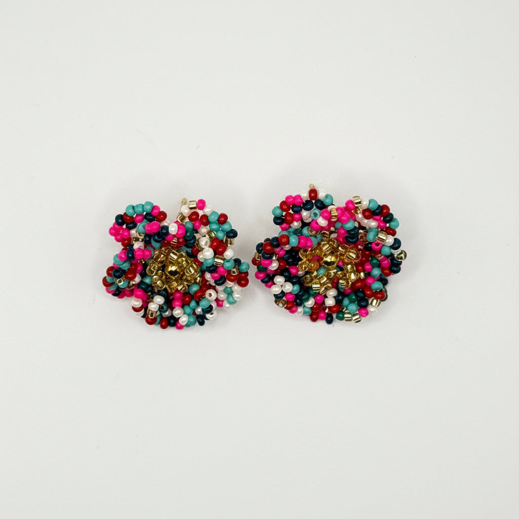 A pair of handmade beaded earrings featuring a gold-toned center surrounded by dense clusters of pink, teal, black, and white seed beads, displayed on a clean white background.