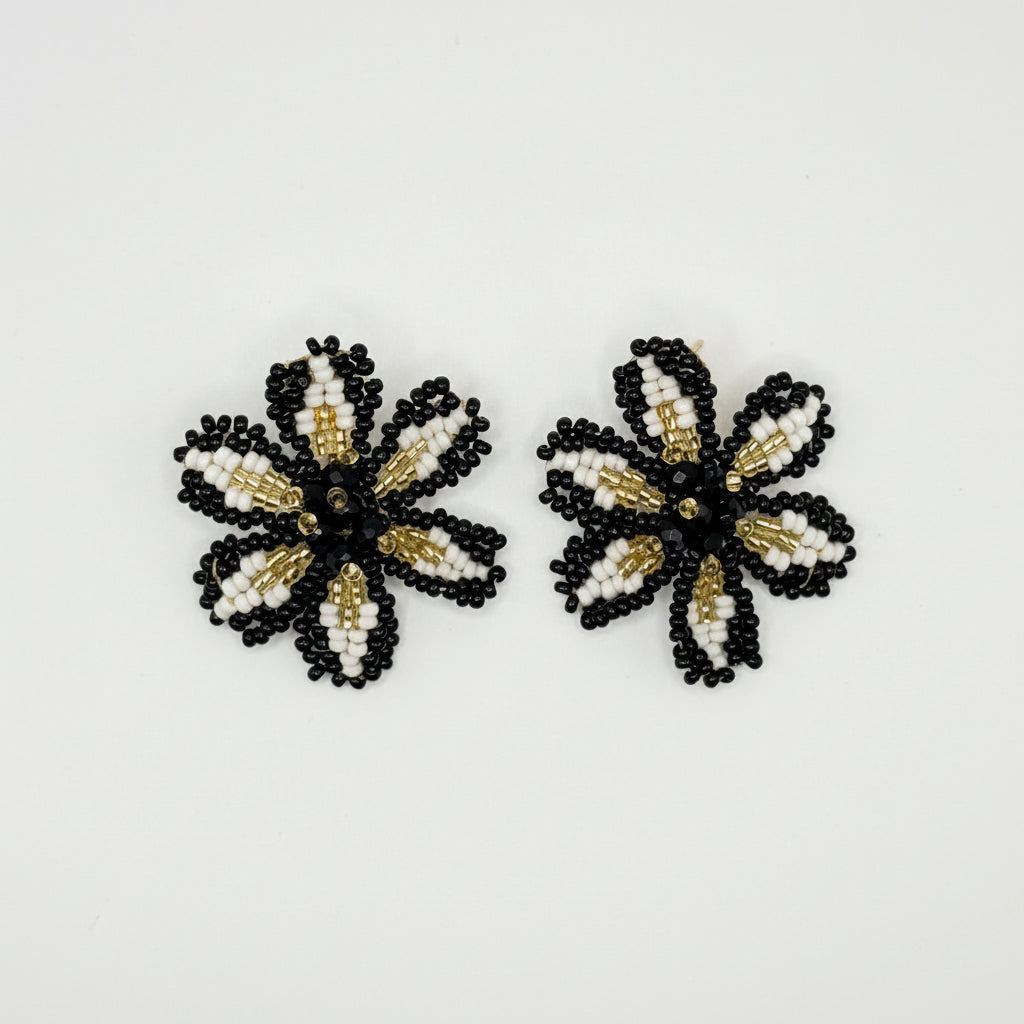 A pair of handmade beaded flower embellishments in black, white, and gold, displayed on a clean white background.