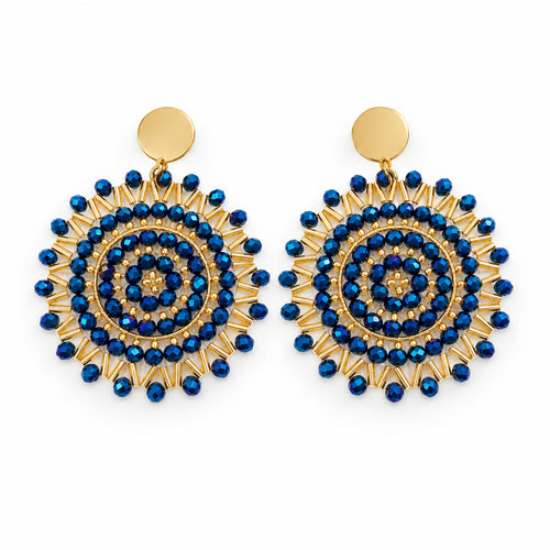 A pair of gold and blue spiral beaded dangle earrings displayed on a clear plastic hanger against a white background.