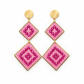 A pair of dangling earrings displayed on a white card against a white background. Each earring has a gold-tone stud with a square pink and magenta geometric pattern drop.