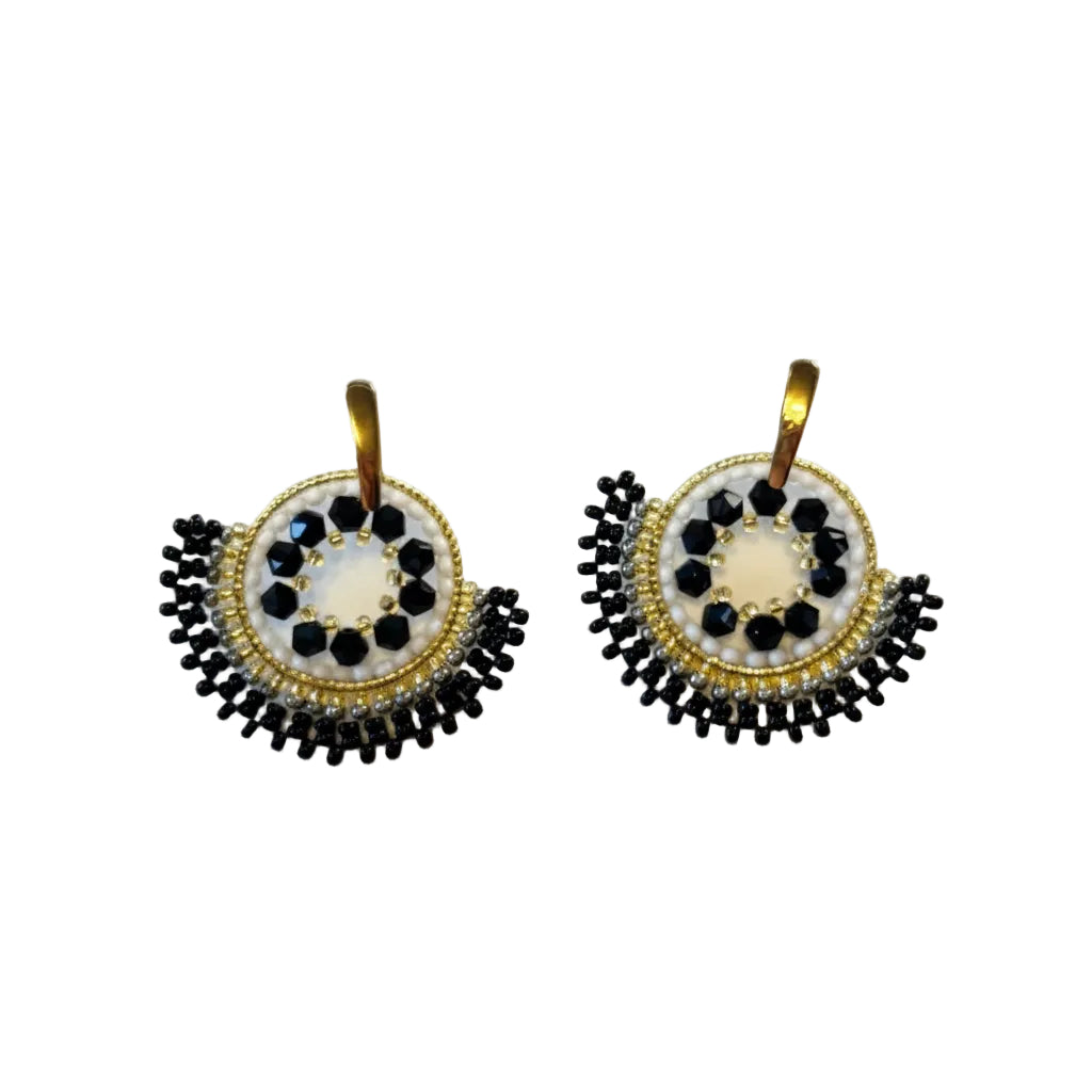 A pair of handmade beaded earrings with gold-tone hooks and circular designs featuring black and white seed beads, displayed on a light off-white background.