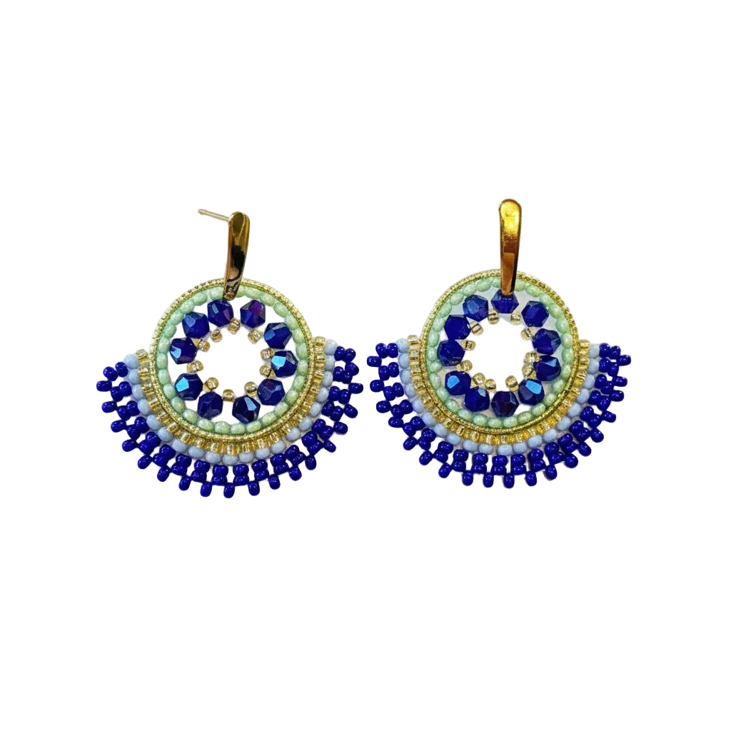 A pair of handmade beaded earrings with gold-toned hooks, featuring circular designs in blue, light blue, and white beads with a dangling fan of dark blue beads.