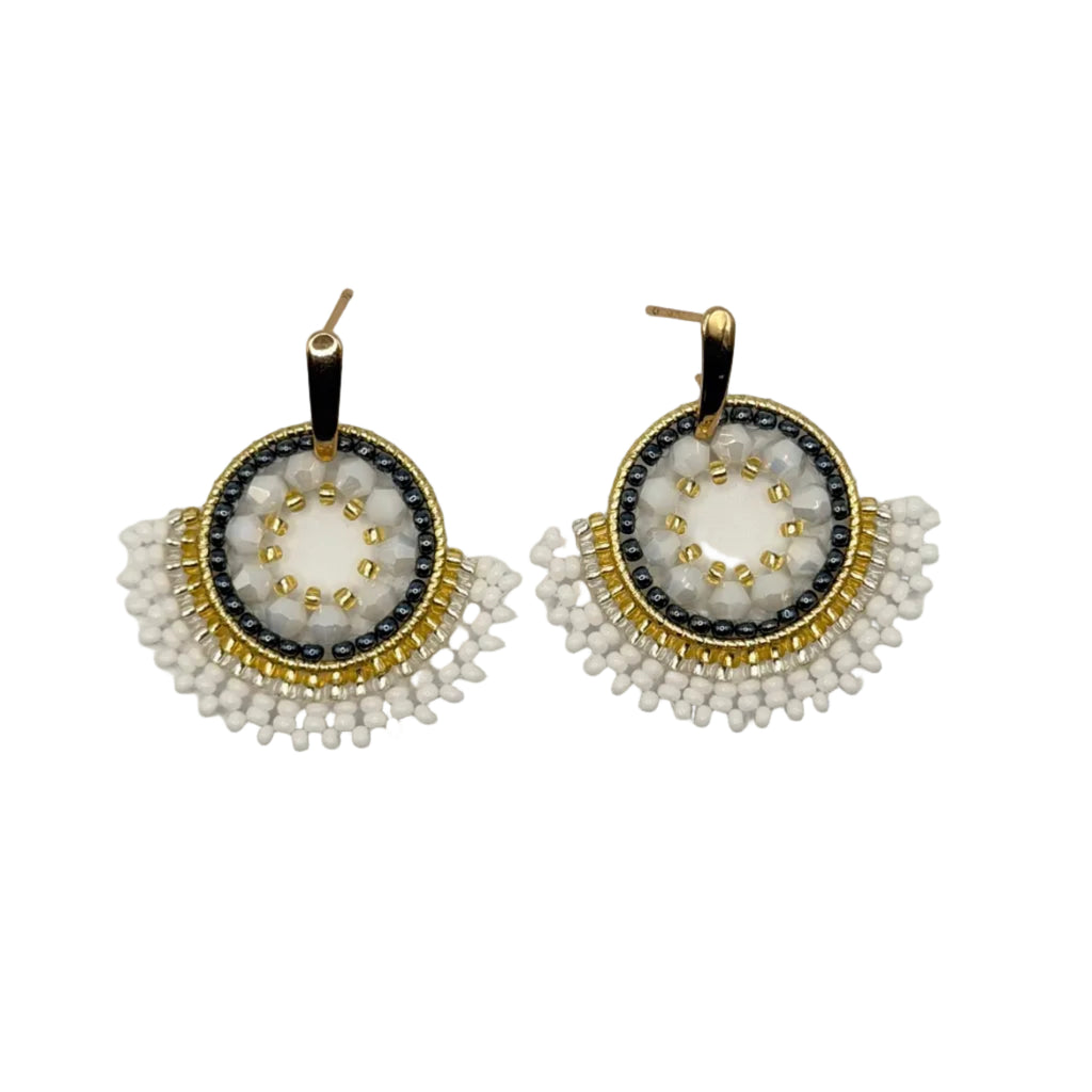 A pair of handmade circular beaded earrings with white seed beads, black accents, gold metal borders, and gold fishhook backs, displayed on a clean white background.
