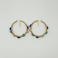 A pair of gold hoop earrings decorated with small blue and green beads, displayed on a plain white background.