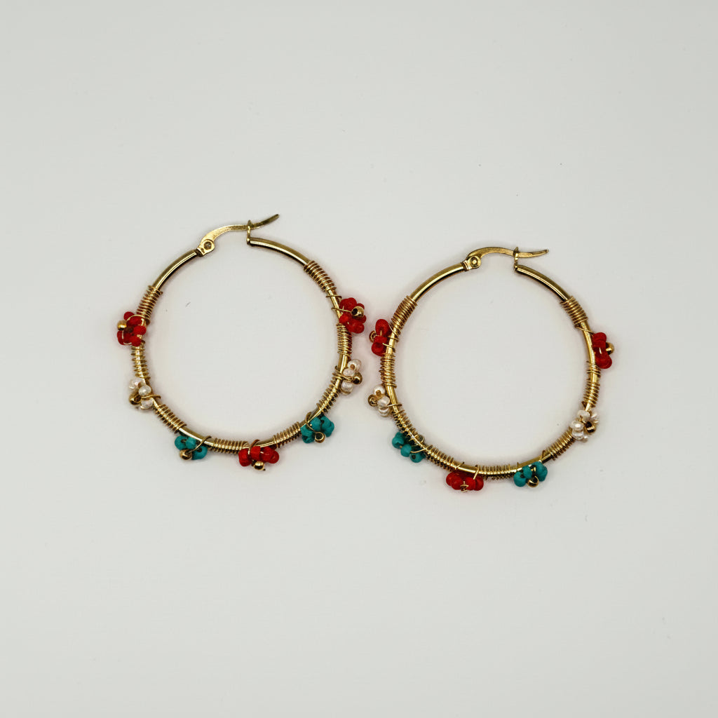 A pair of gold hoop earrings decorated with small red and green beads, displayed on a plain light gray background.