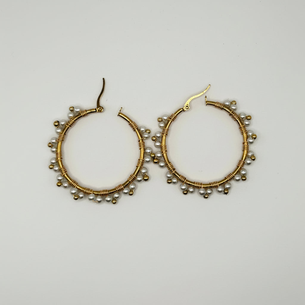 A pair of gold hoop earrings decorated with small silver beads along the outer edge, displayed on a plain light gray background.