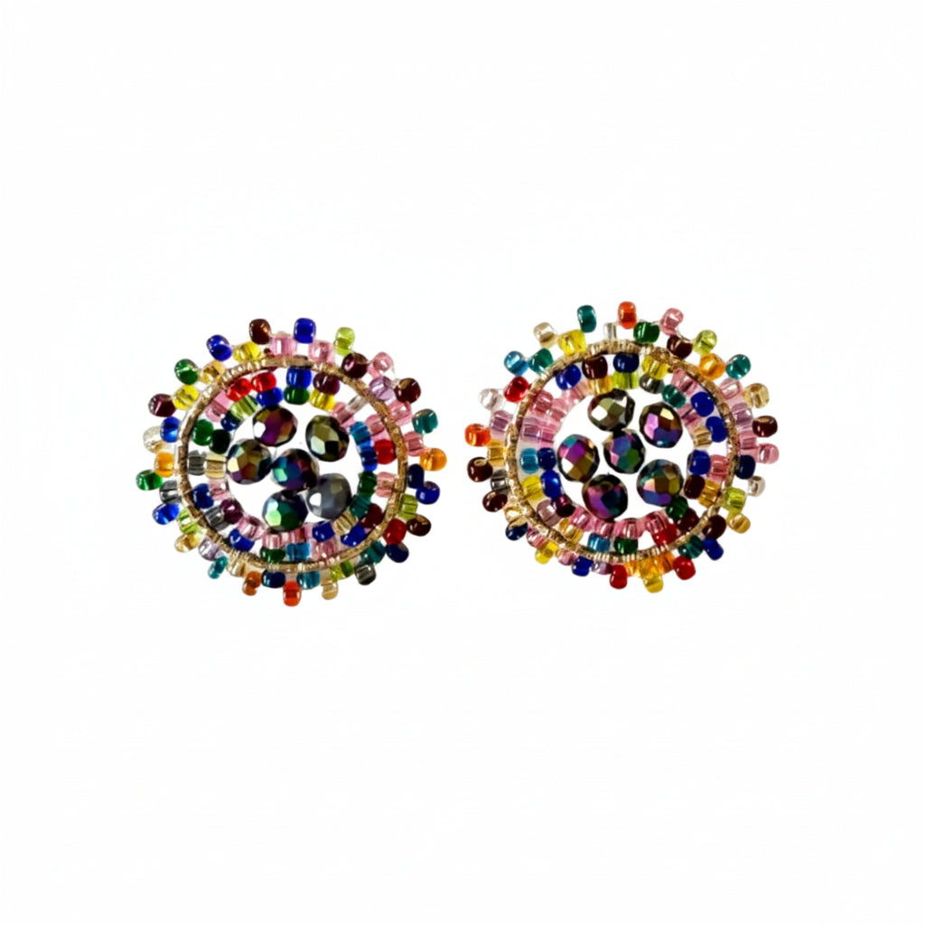 A pair of round stud earrings decorated with colorful seed beads and clear faceted center stones, displayed on a plain light gray surface.