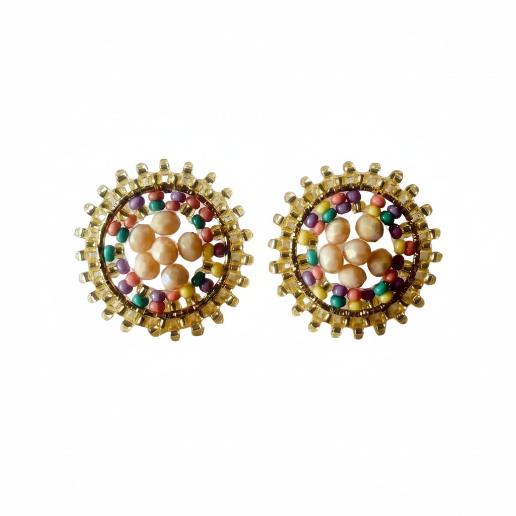 A pair of round gold-tone stud earrings featuring a central cluster of peach-pink pearls surrounded by small multicolored beads and a textured gold border, set against a plain off-white background.