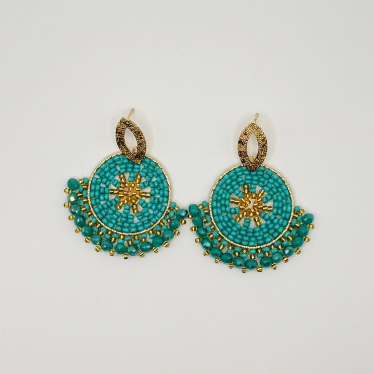 A pair of handmade beaded earrings featuring turquoise blue beads and gold metal details, displayed on a clean white background.