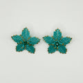 A pair of handmade turquoise flower-shaped stud earrings with gold beaded edges, displayed on a clean white background.