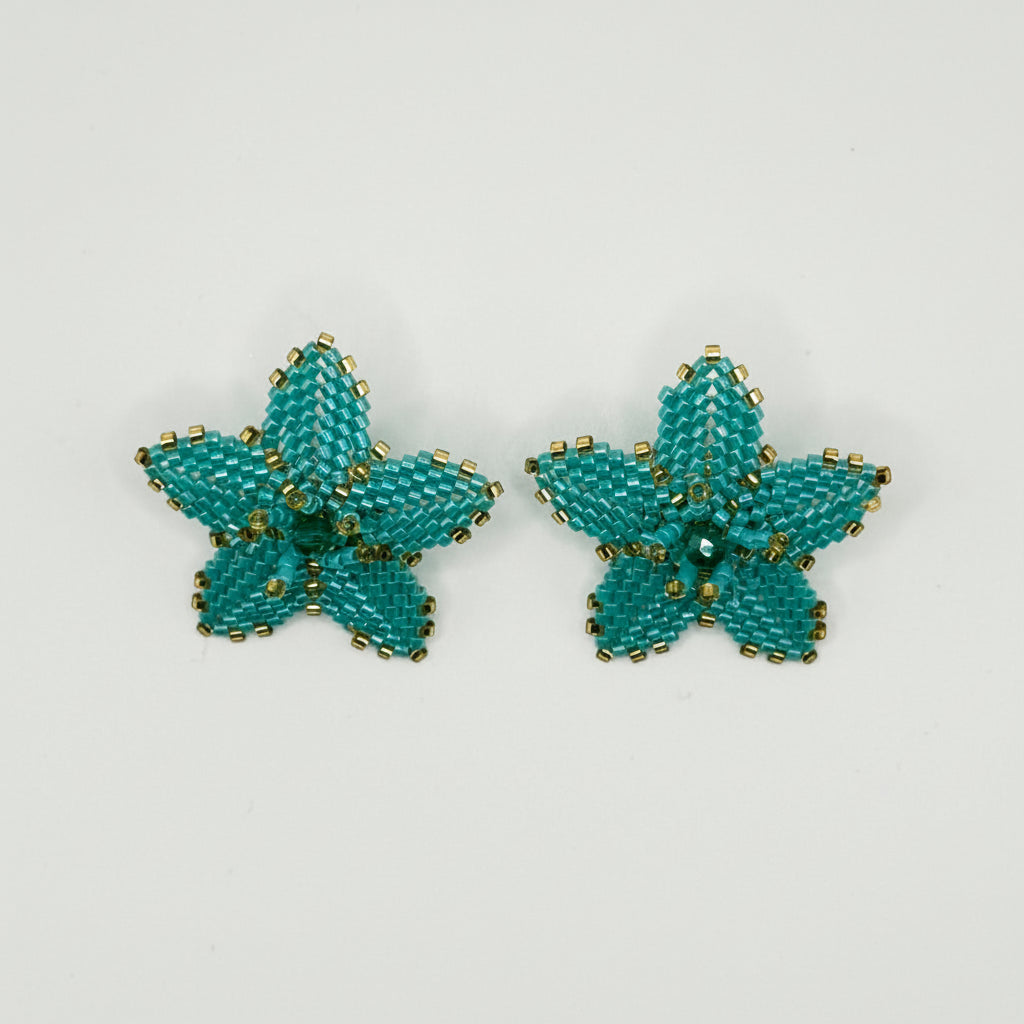 A pair of handmade turquoise flower-shaped stud earrings with gold beaded edges, displayed on a clean white background.