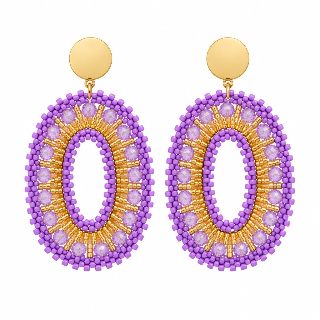 A pair of handmade oval drop earrings with purple and gold beaded fringe, displayed on a white surface.