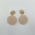 Pair of beige beaded earrings on a light gray background