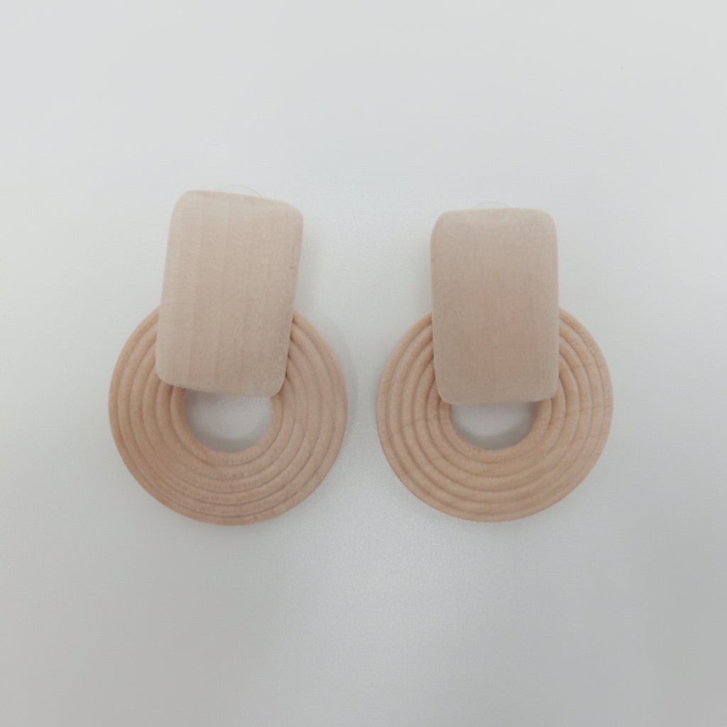 Pair of beige circular earrings on a light gray background