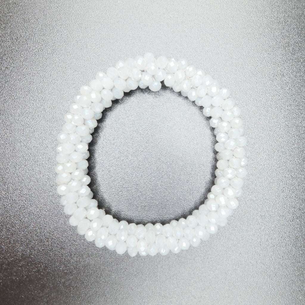 White beaded bracelet on a textured gray surface