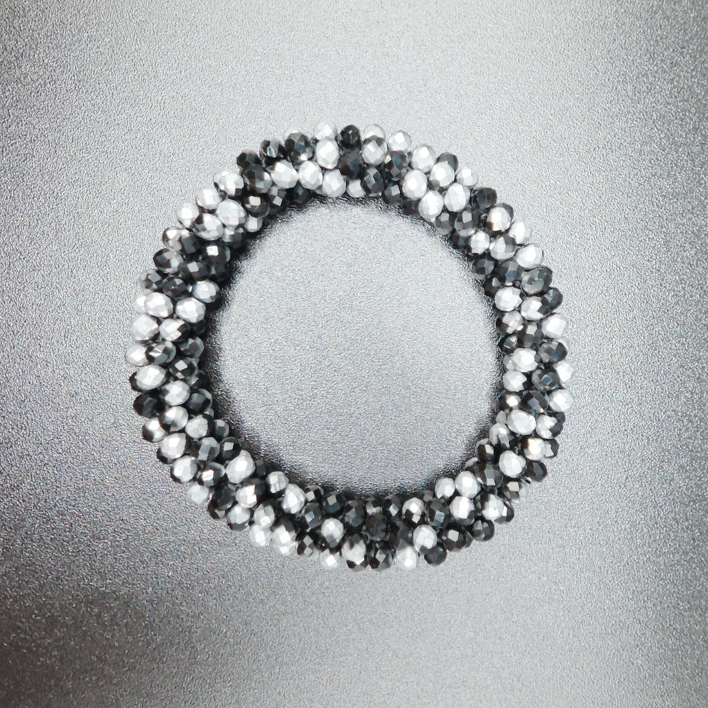 Silver beaded ring on a reflective silver surface