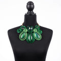 A green soutache statement necklace displayed on a black mannequin bust against a white background.