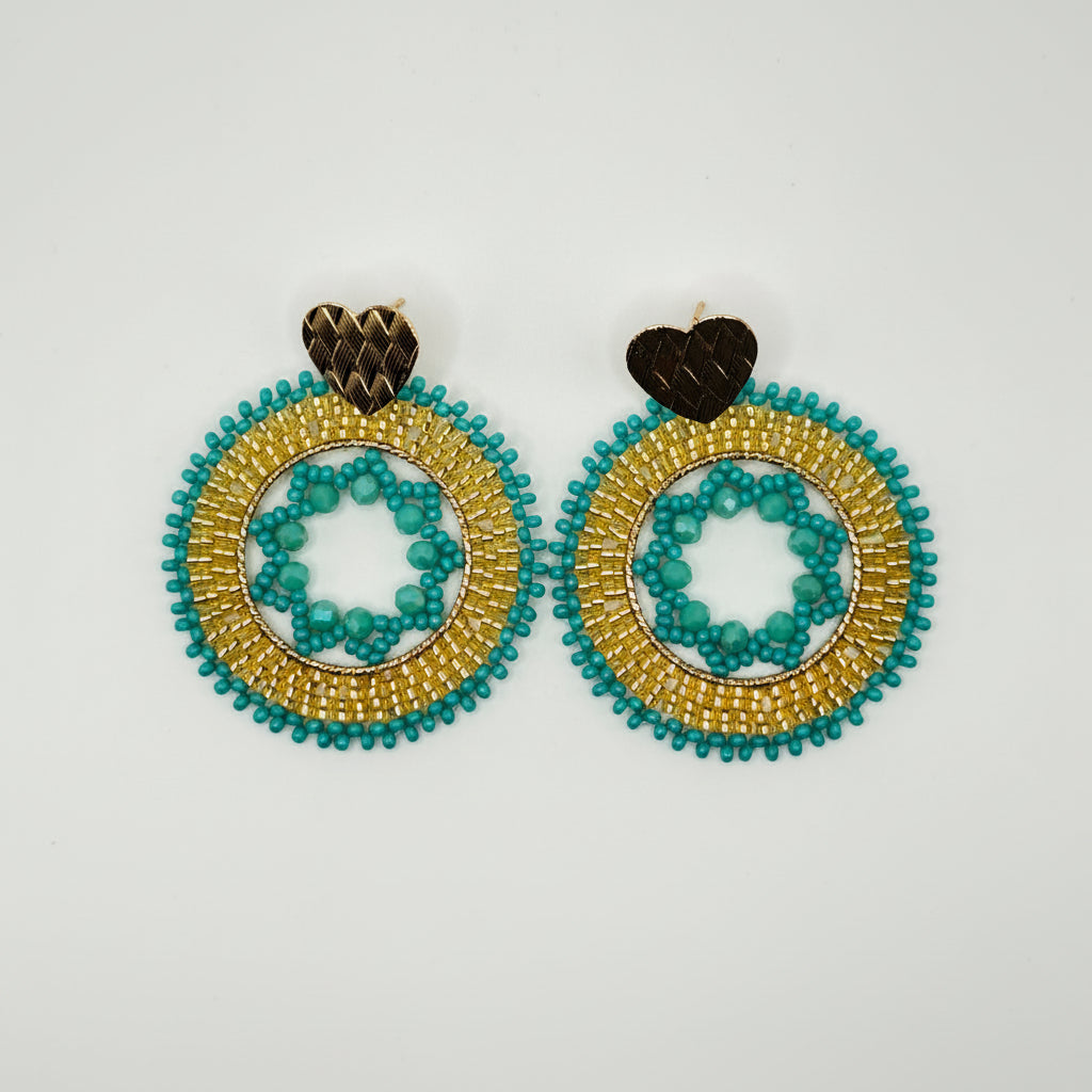 A pair of handmade beaded earrings featuring gold and turquoise blue circular patterns with small brown heart-shaped studs, displayed on a clean white background.