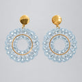 A pair of light blue beaded hoop earrings with gold-tone posts and inner hoops, displayed on a clear plastic card against a white background.