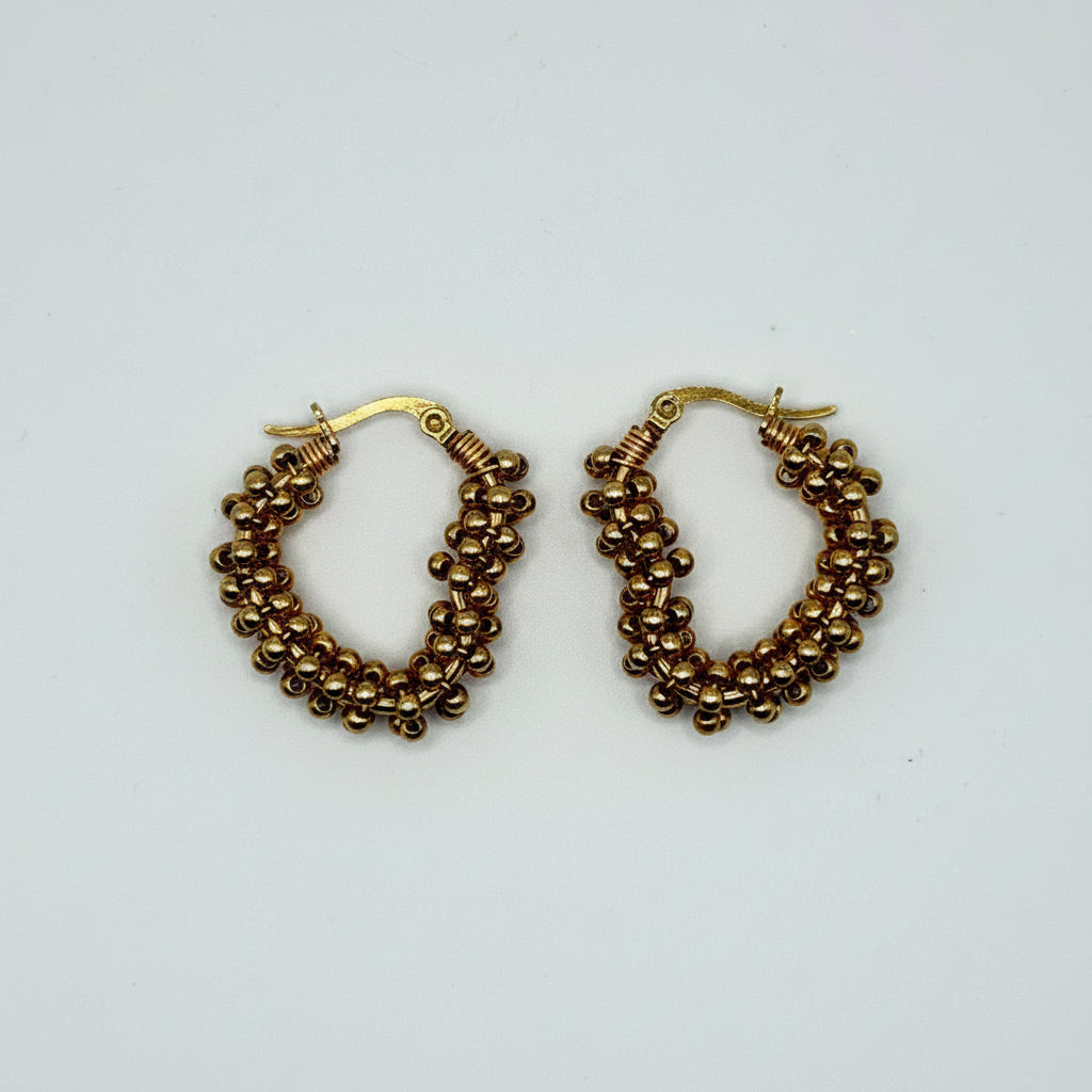 A pair of gold-tone hoop earrings with textured, beaded triple-row bands, displayed on a clean white background.