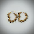 A pair of gold-tone hoop earrings decorated with small white pearl-like beads, displayed on a plain light gray background.