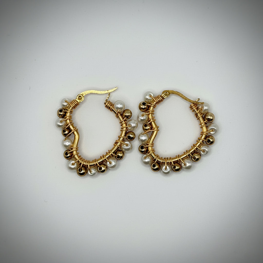 A pair of gold-tone hoop earrings decorated with small white pearl-like beads, displayed on a plain light gray background.