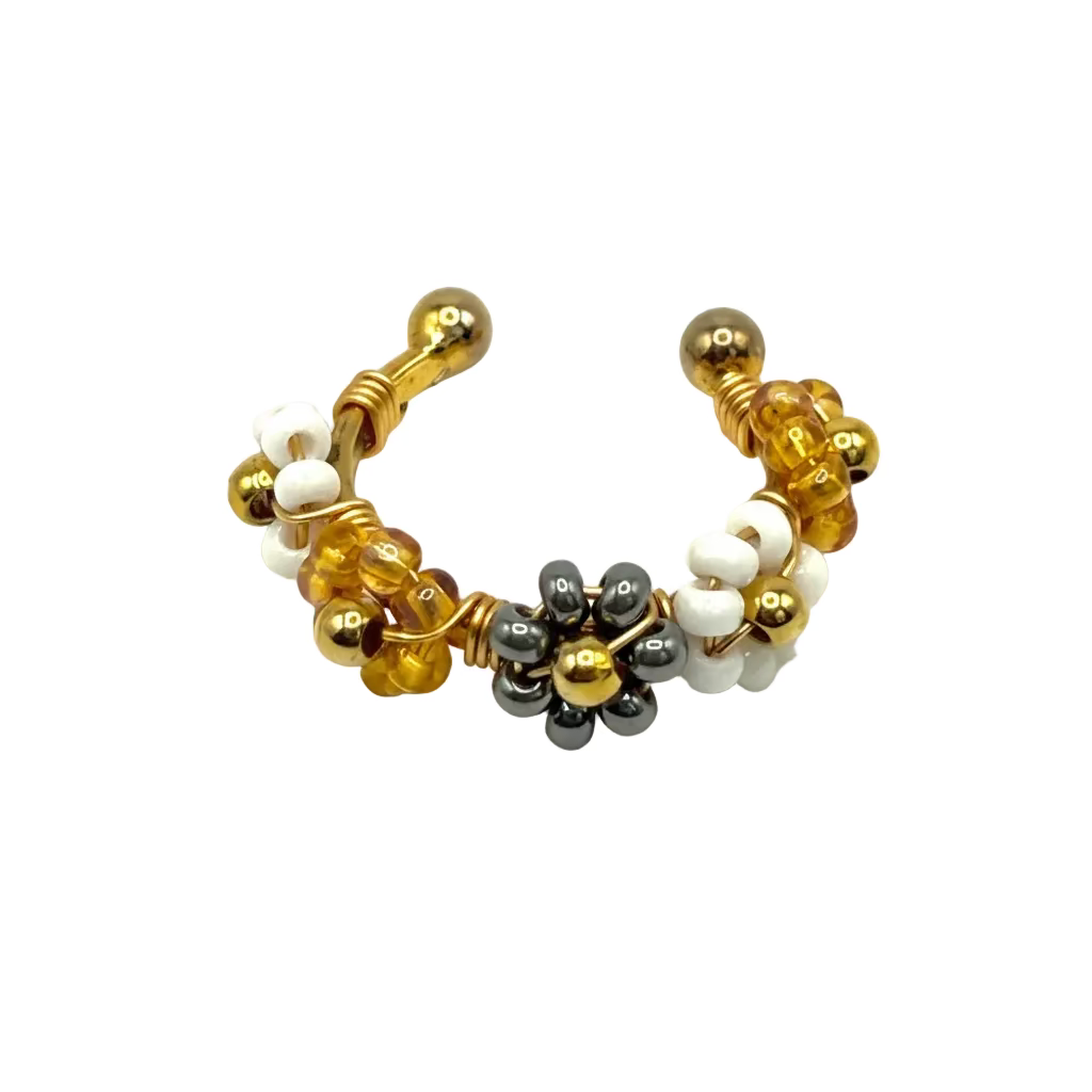 Beaded earring with gold, white, and black beads on a light gray background