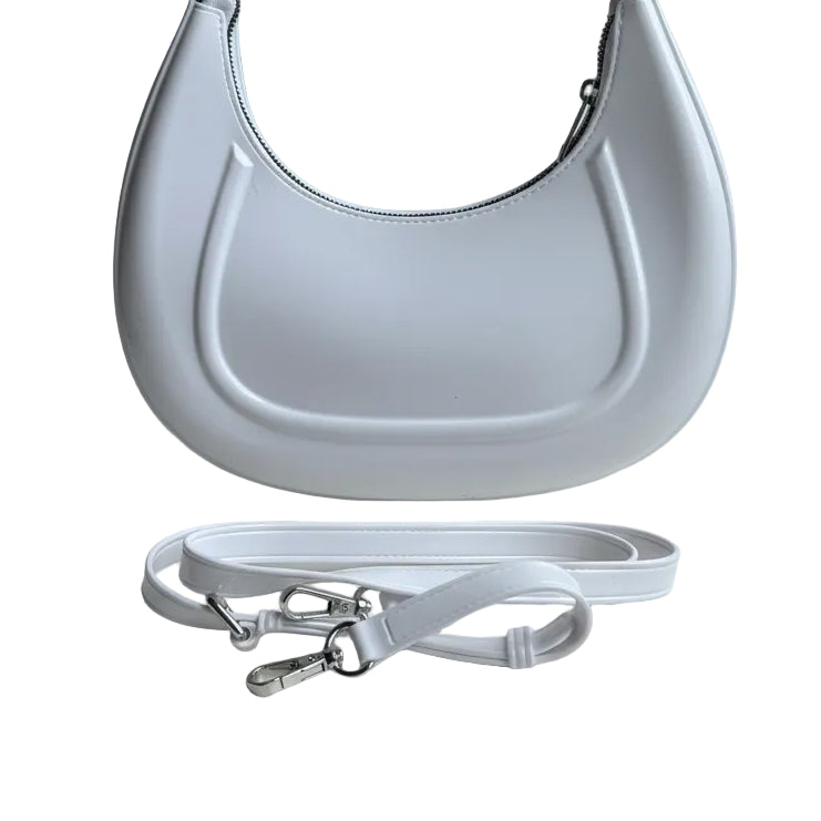 White handbag with a matching strap on a light surface