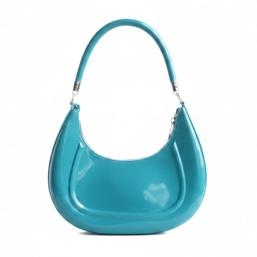 Blue handbag held by a hand against a white background