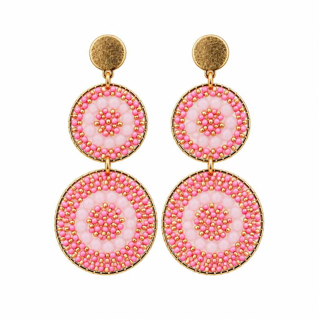A pair of round drop earrings with pink and white floral mandala patterns, suspended from gold-toned stainless steel posts on a white display card.