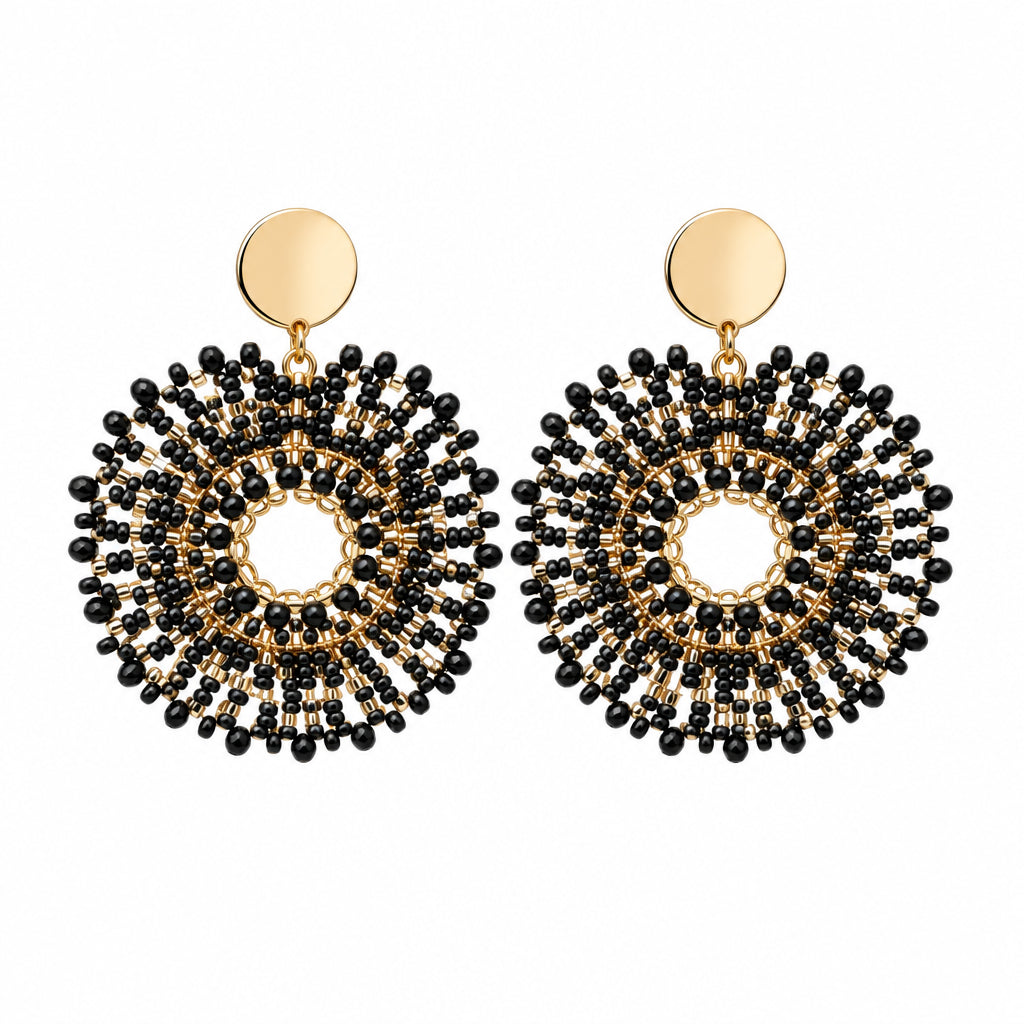 A pair of black beaded hoop earrings with gold-tone studs and a central white pearl, displayed on a white backing card.