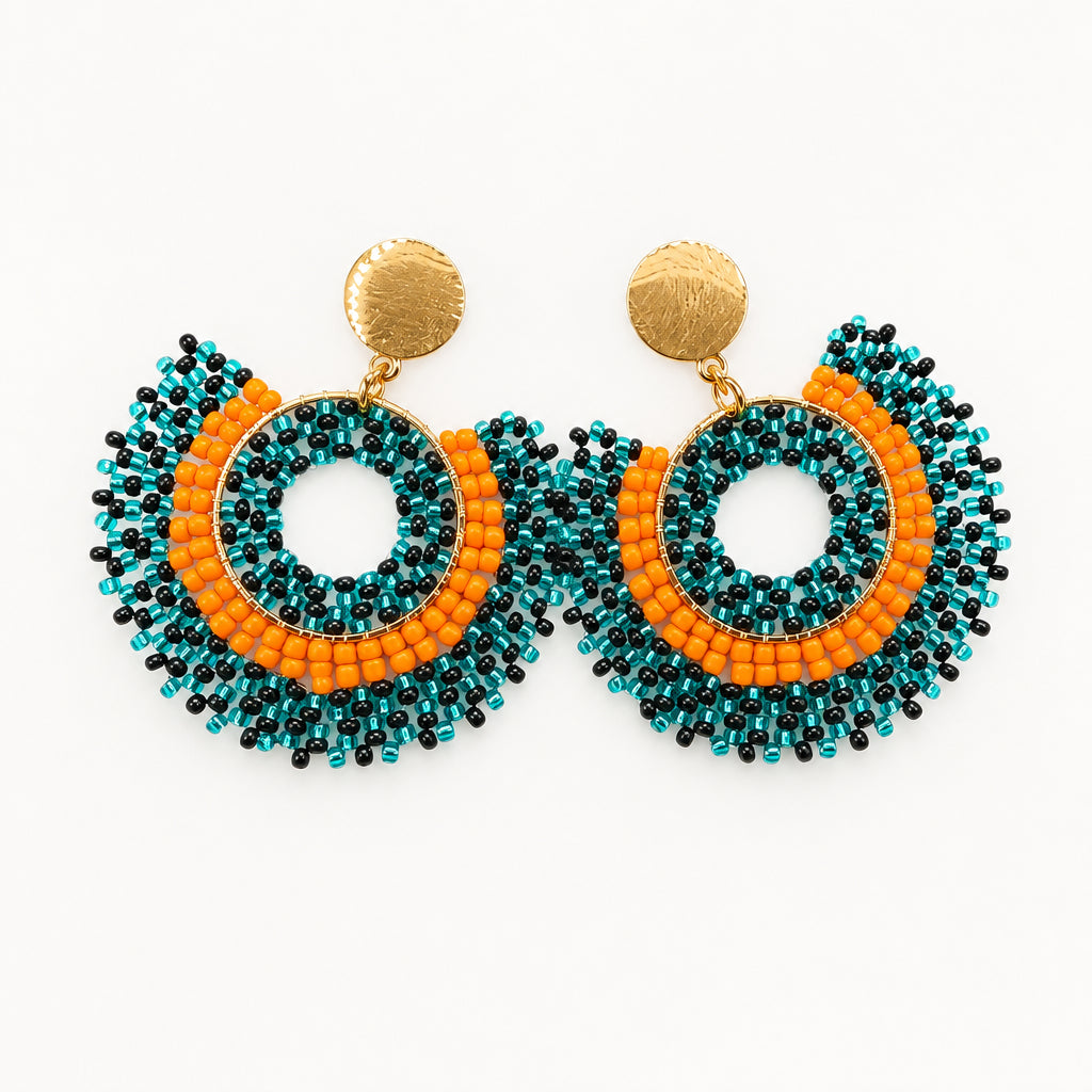 A pair of handmade beaded hoop earrings with gold-tone studs, featuring a teal blue and orange beaded fringe design, displayed on a small white card against a white background.