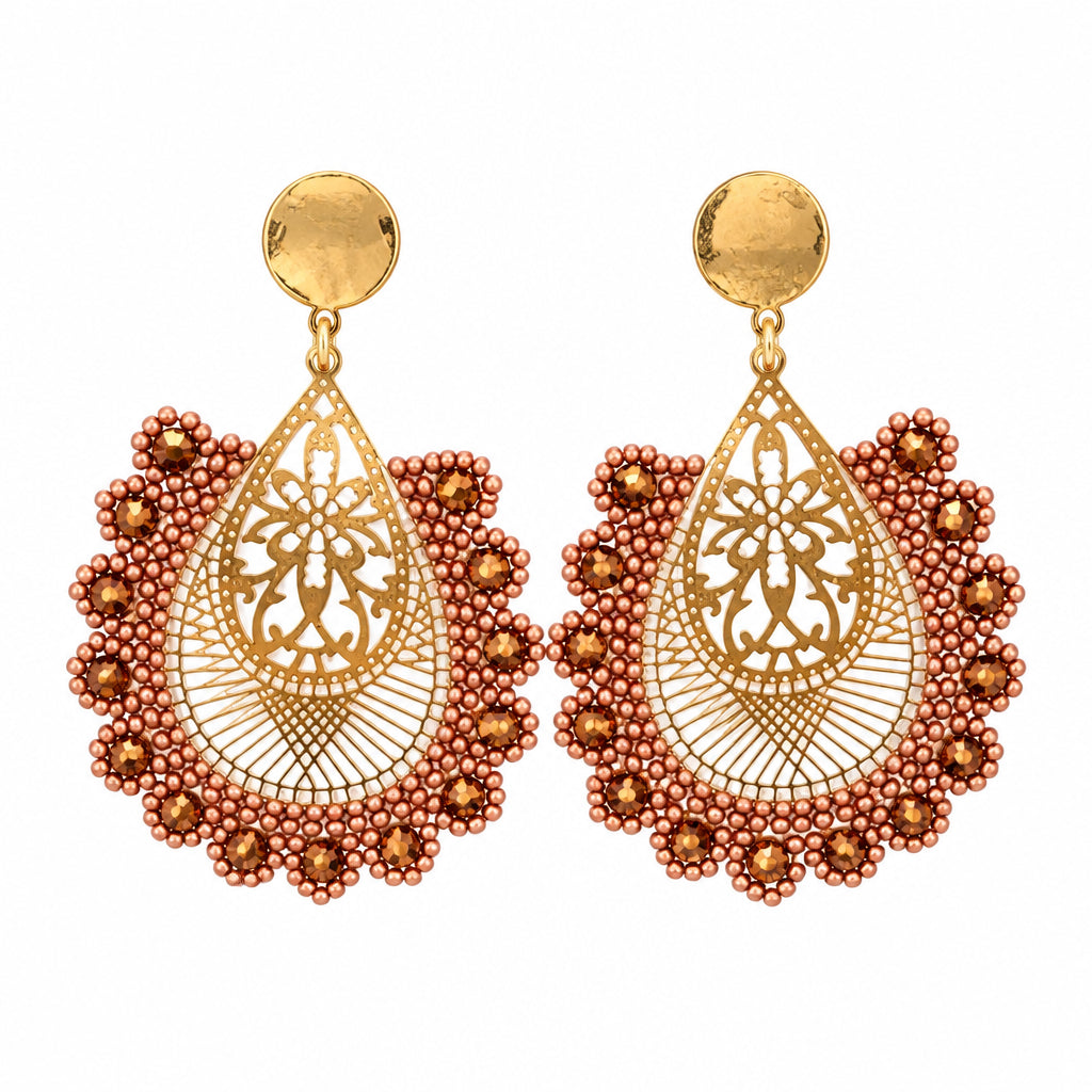 A pair of ornate gold-toned dangle earrings with intricate filigree detailing and red beaded scalloped borders, displayed on a white plastic card against a white background.