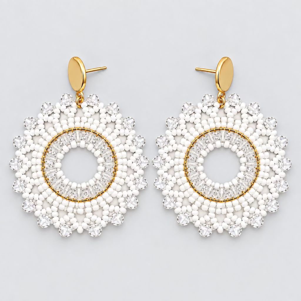 A pair of handmade circular dangle earrings with gold-tone metal frames and posts, decorated with white and light blue faceted beads, displayed on a dark gray surface.