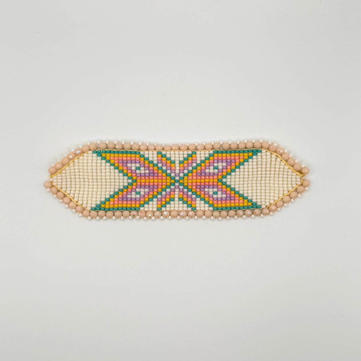 A handmade beaded bracelet with a geometric pattern, featuring a central orange and purple chevron motif surrounded by green and blue details, finished with a border of small beige beads on a plain white background.