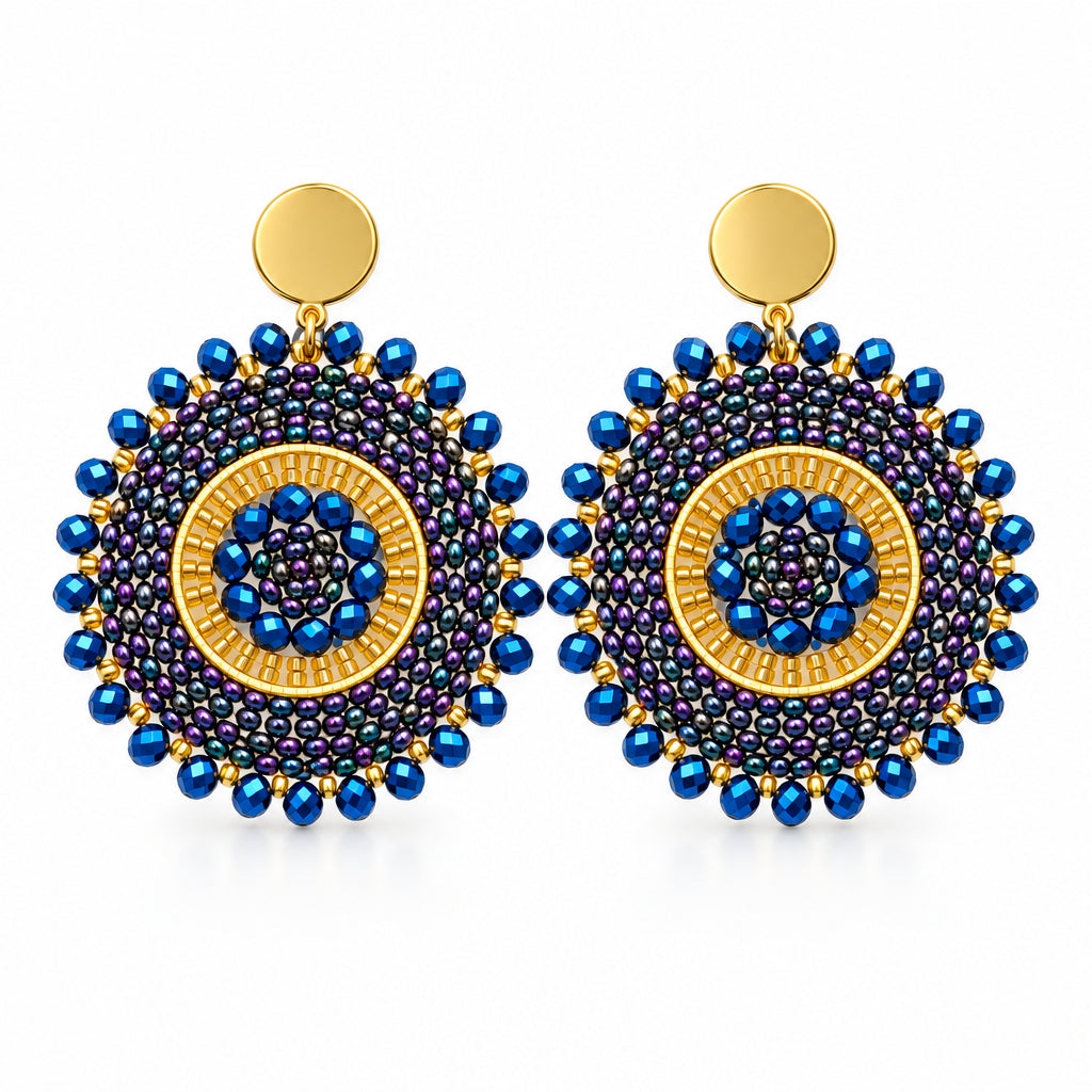 A pair of handmade circular beaded earrings with blue, purple, and gold concentric patterns, displayed on a white background.