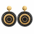 A pair of bohemian-style dangle earrings with intricate black and gold circular patterns, displayed on a small white card against a white background.