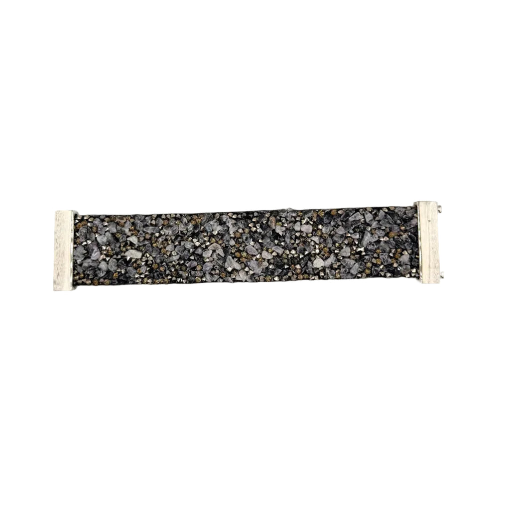 A fabric wristband or bracelet featuring a black and gray speckled terrazzo pattern with white elastic end loops, shown against a plain light gray background.