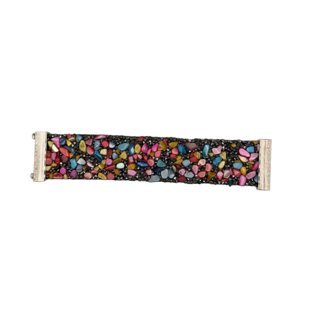 A horizontal fabric bracelet or wristband featuring a colorful pebble mosaic pattern on a black background, finished with white fabric cuffs on both ends, shown against a plain light gray background.