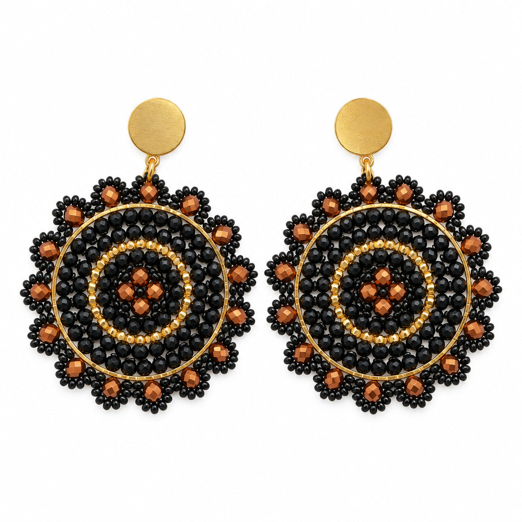 A pair of bohemian-style circular drop earrings with intricate black and orange mandala patterns on gold-tone metal, displayed on a white card against a white background.