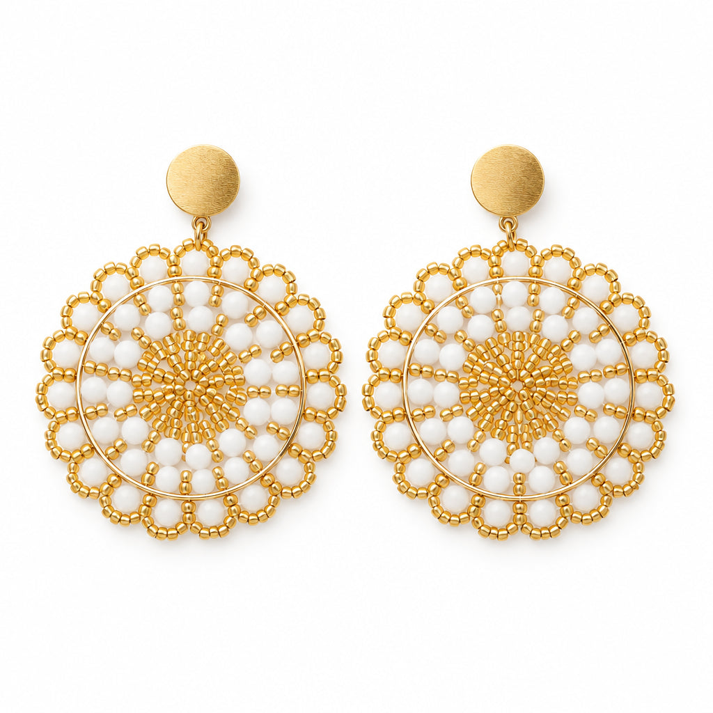 A pair of gold and white beaded dangle earrings displayed on a white card against a white background.