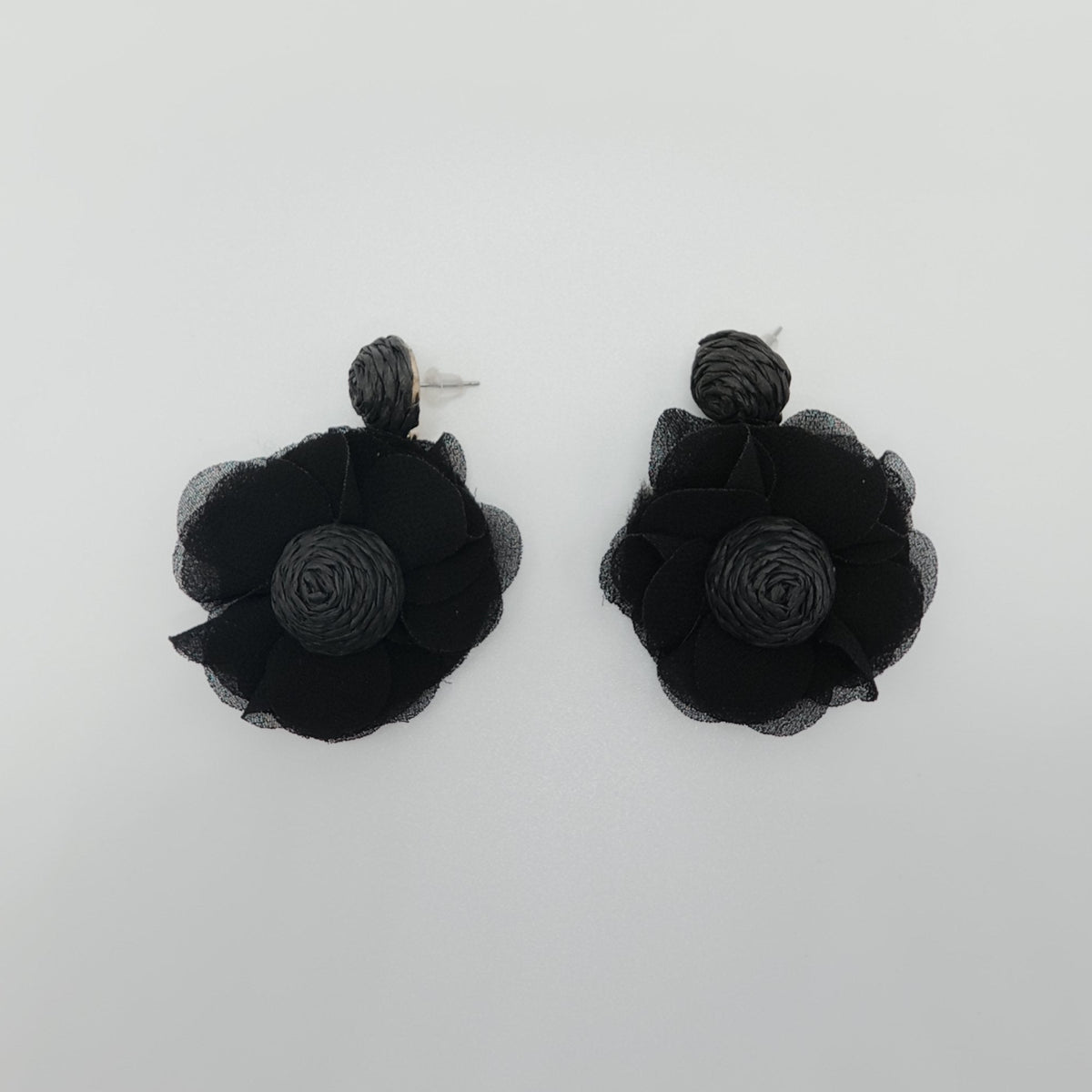 Black flower-shaped earrings on a white background