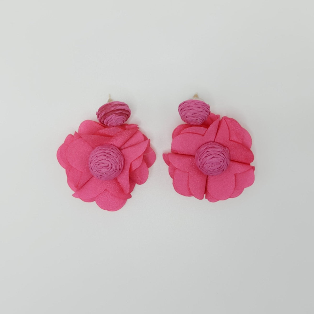 Pink flower-shaped earrings on a white background