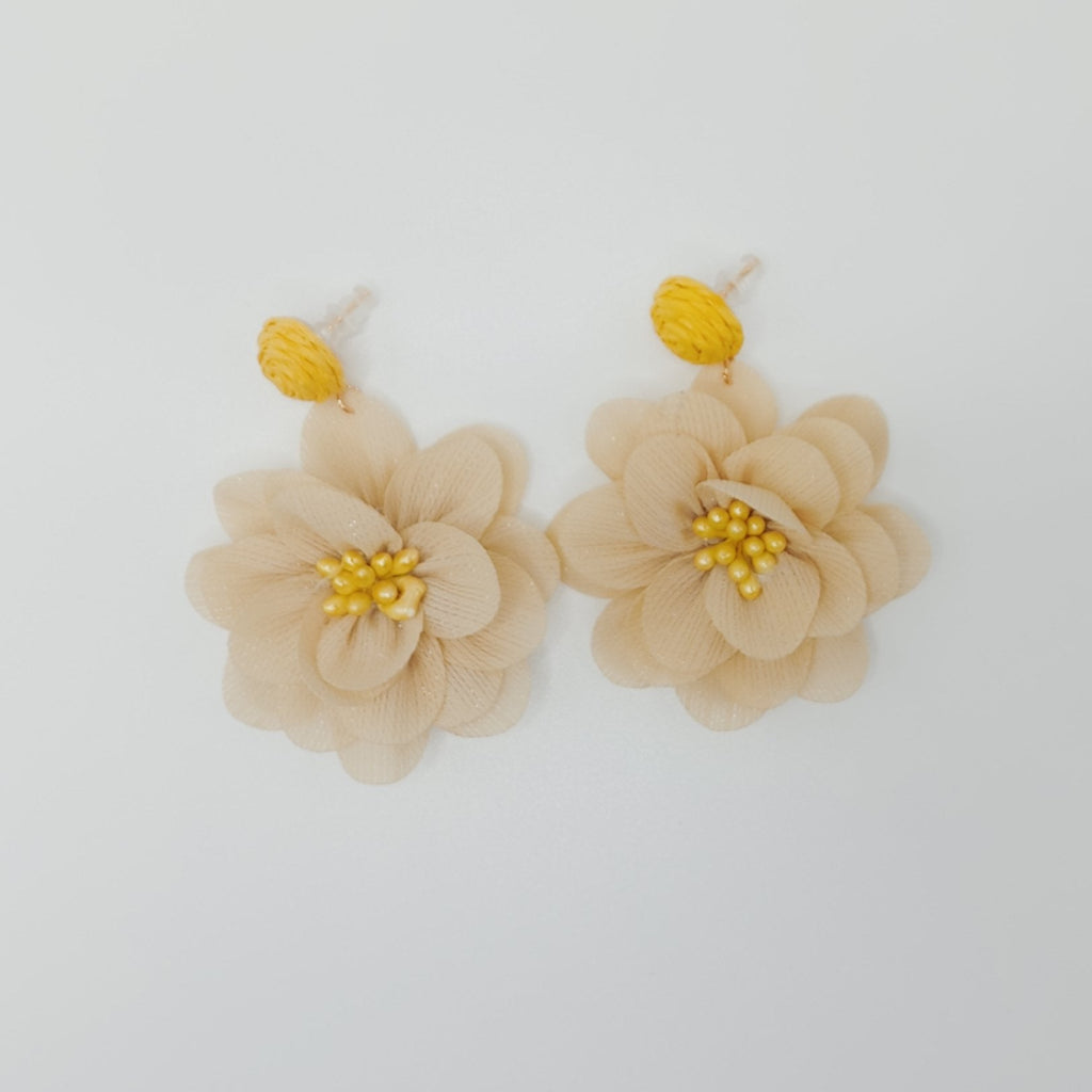 Beige flower earrings with yellow centers on a white background