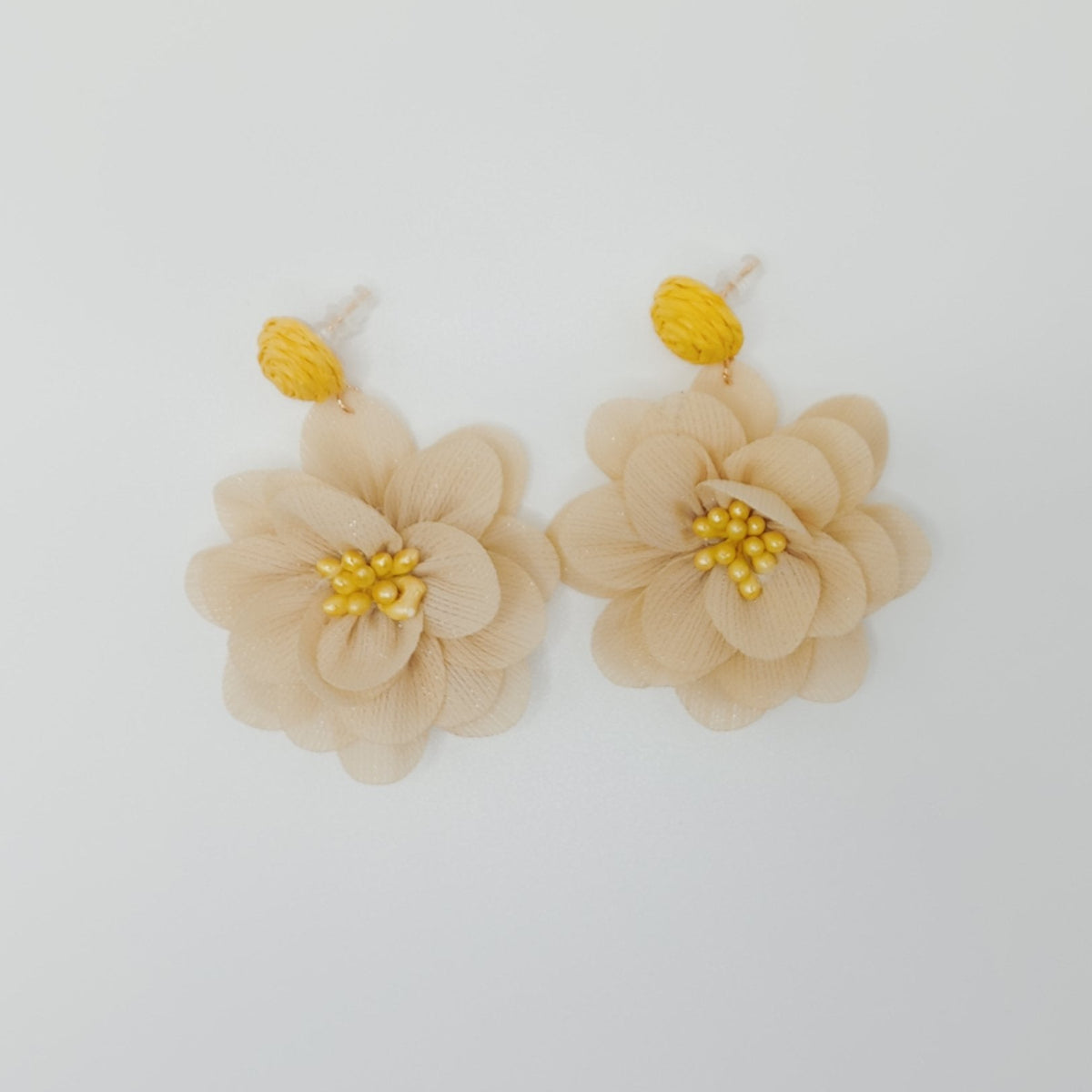 Beige flower earrings with yellow centers on a white background
