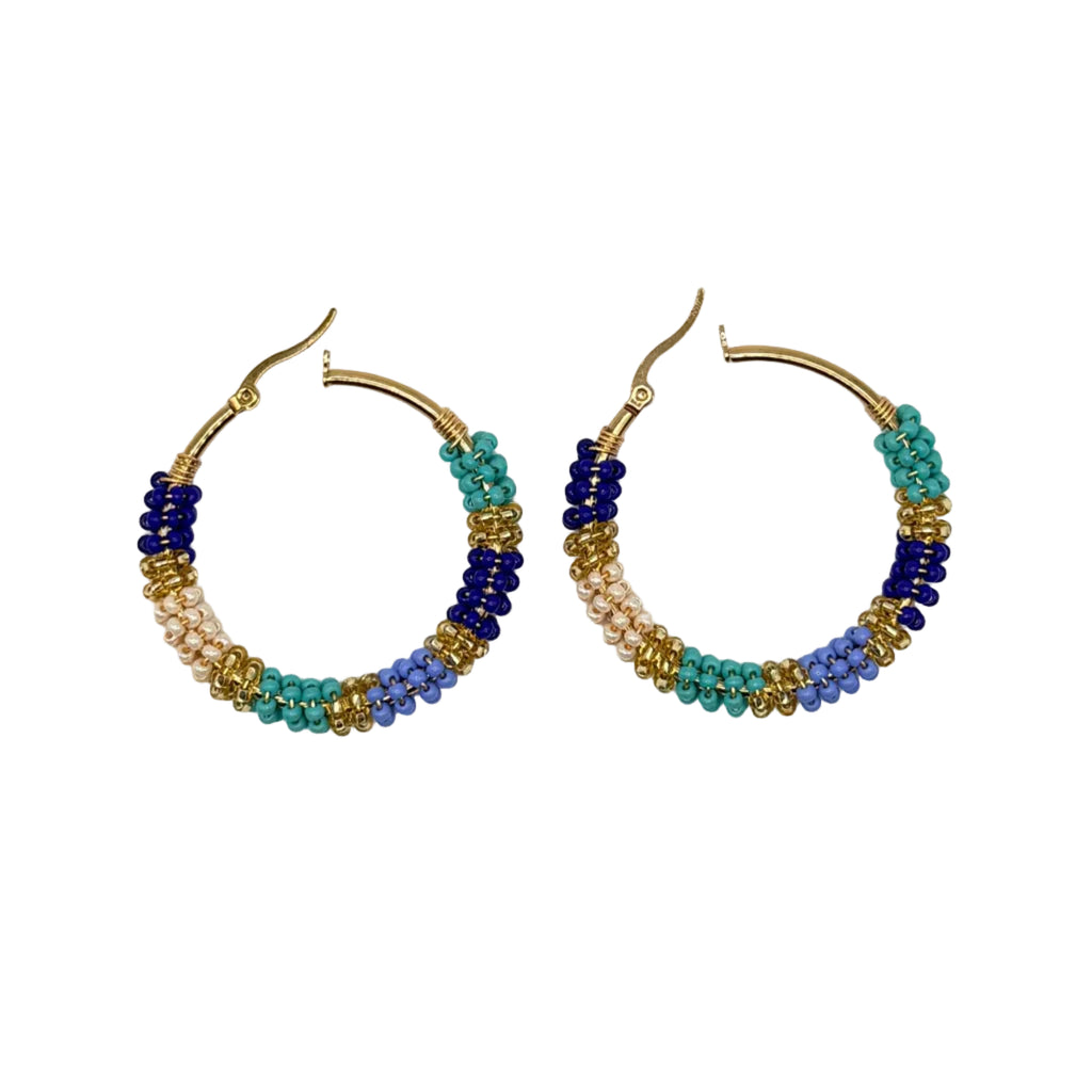 A pair of handmade gold hoop earrings decorated with multi-colored seed beads in blue, teal, lavender, and white, displayed on a clean white background.