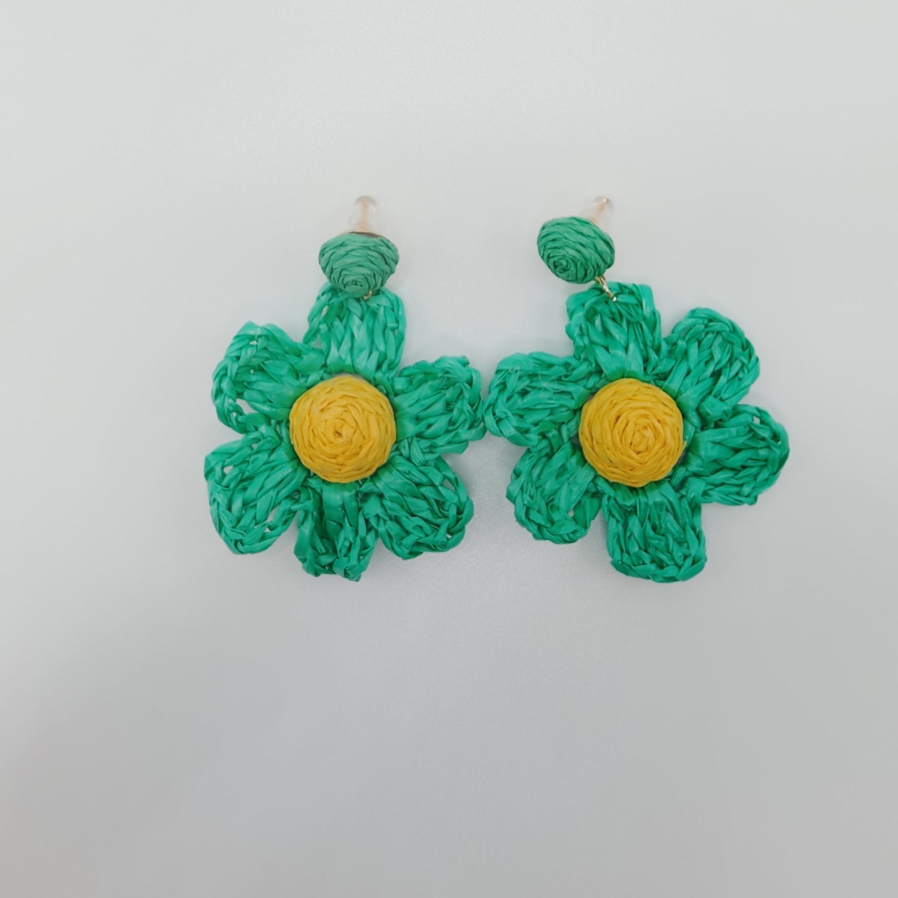 Green flower-shaped earrings with yellow centers on a white background