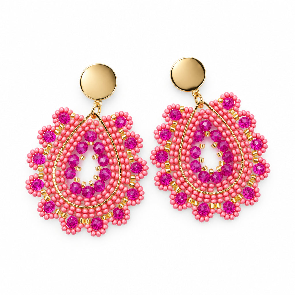 A pair of handmade beaded dangle earrings with bright pink and gold seed beads, displayed on a small white card against a white background.