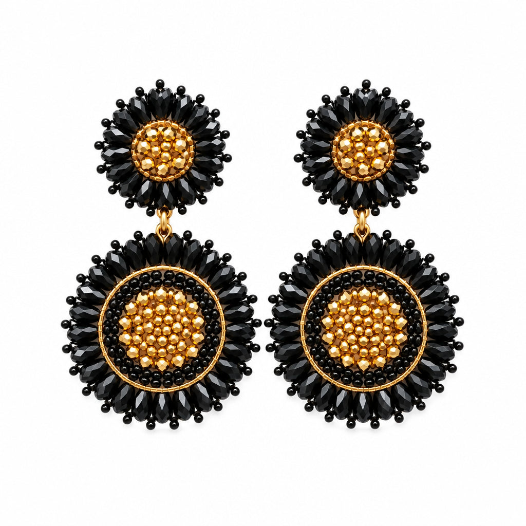 A pair of black and gold beaded dangle earrings displayed on a small clear card against a white background.