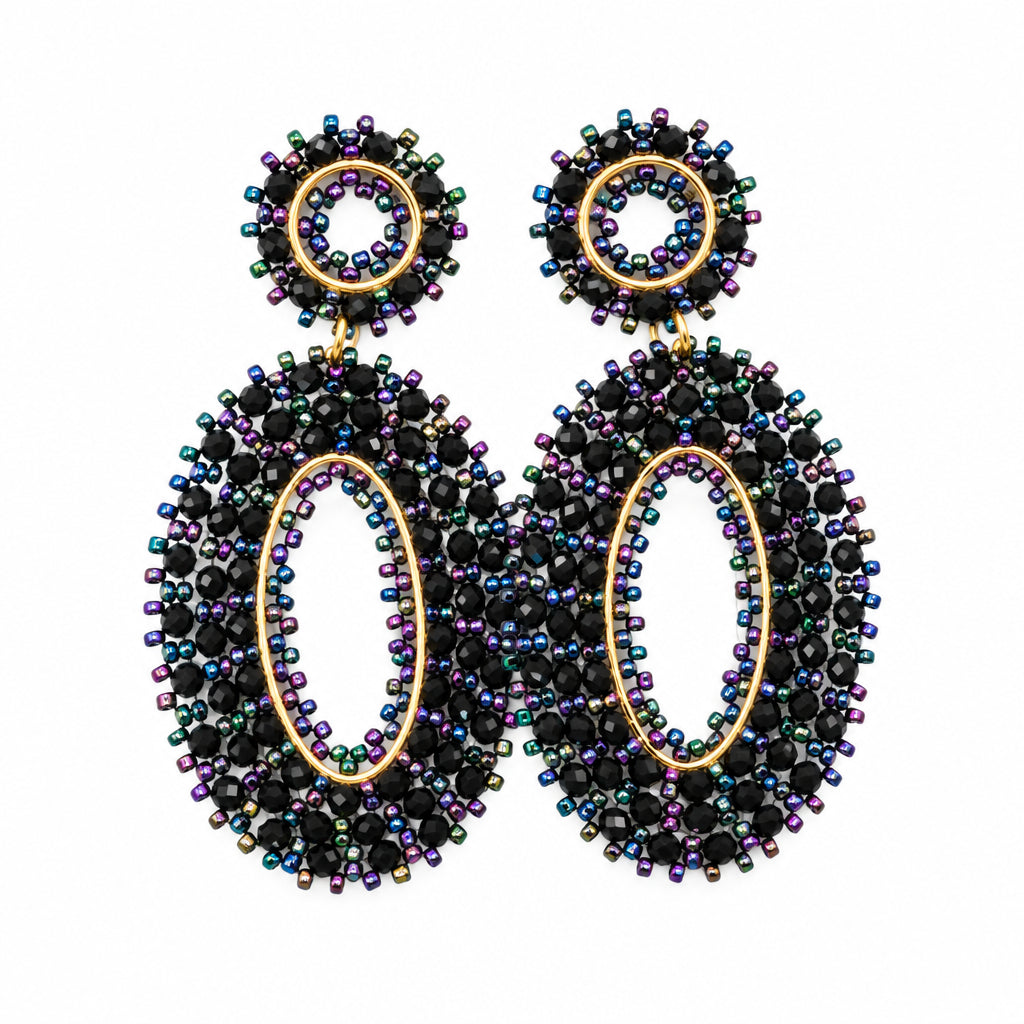 A pair of statement dangle earrings with oval-shaped dark iridescent rhinestone bodies and round faceted crystal studs, displayed on a white jewelry bust.